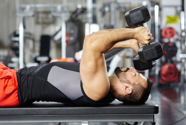 Homem fazendo exercícios para tríceps testa com halteres